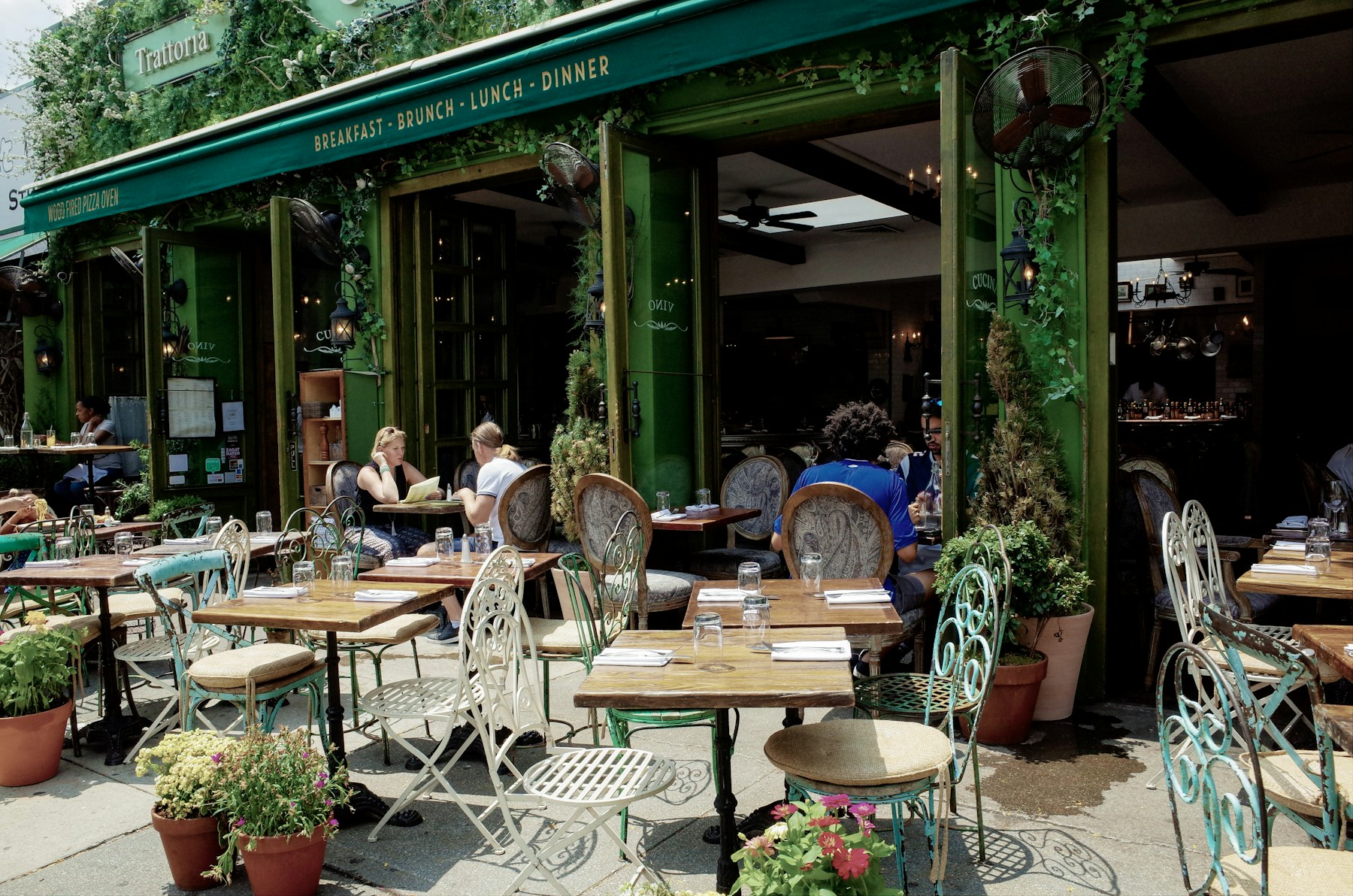 Green cafe patio with tables and plants in daylight